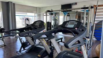 Ein Fitnessstudio mit Laufbändern, Kraftgeräten und einem großen Fenster.