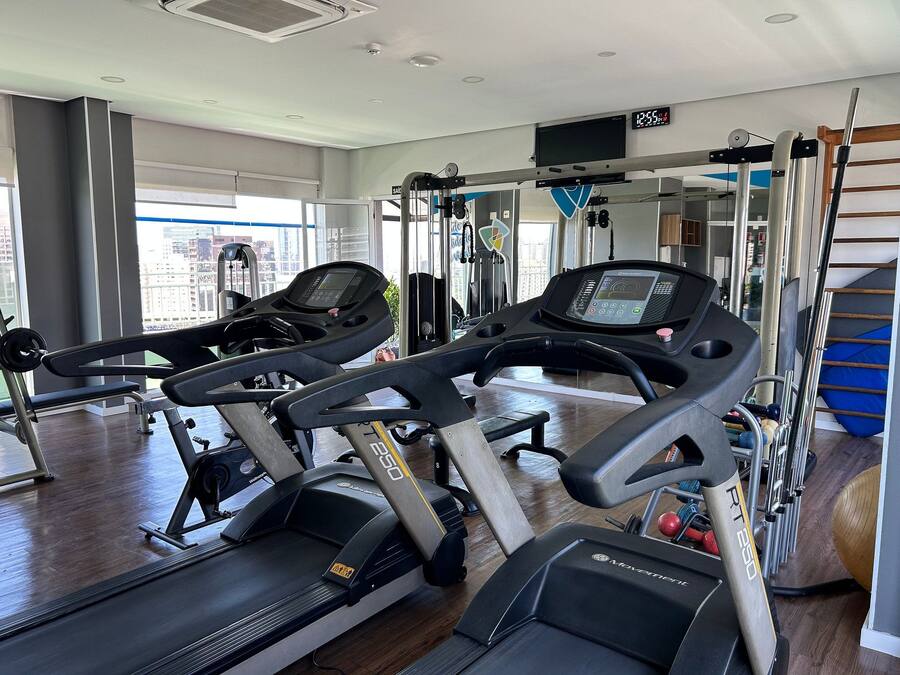 Ein Fitnessstudio mit Laufbändern, Kraftgeräten und einem großen Fenster.
