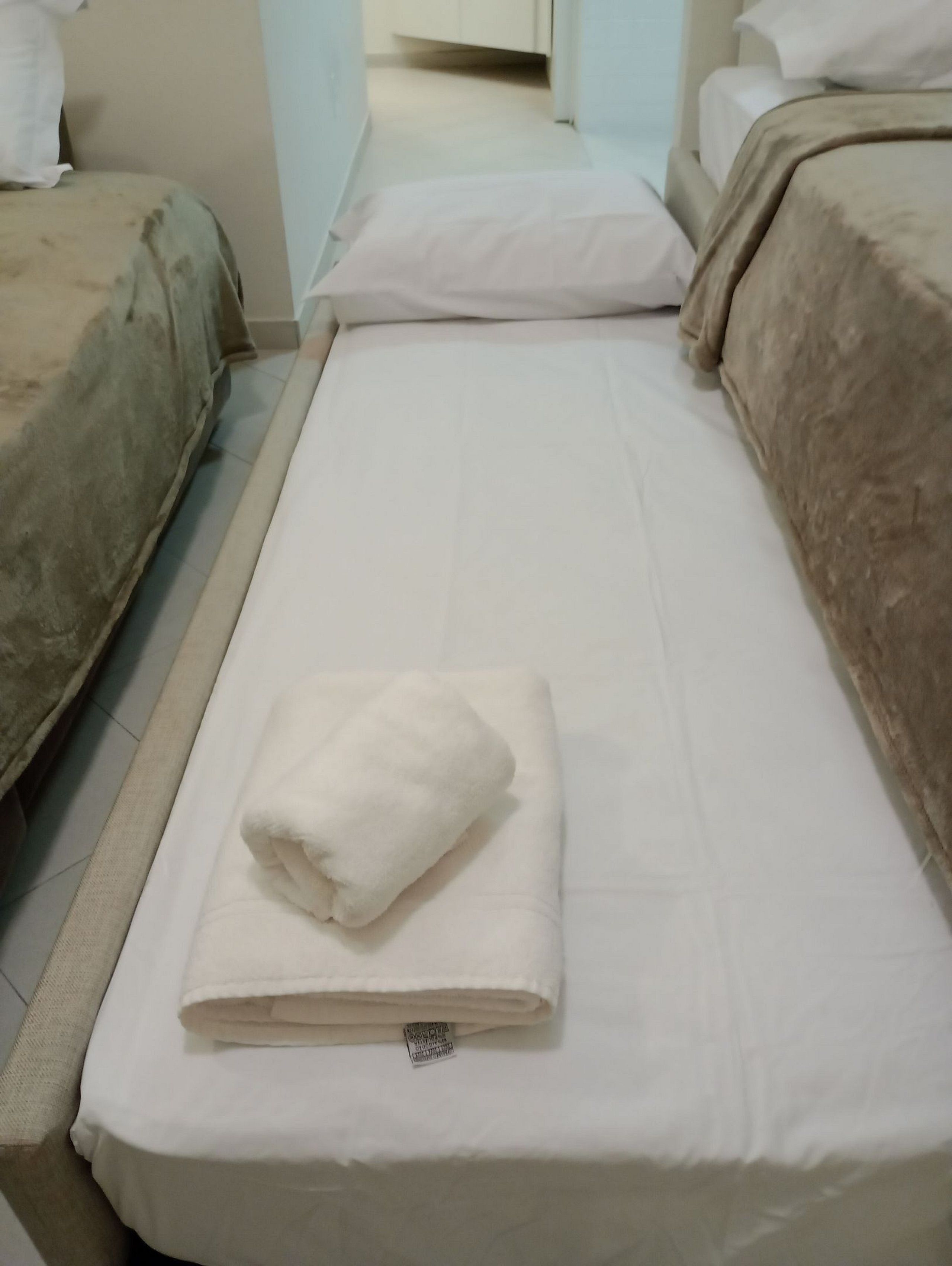Quarto de hotel com uma cama, outra cama e uma terceira cama ao fundo.
