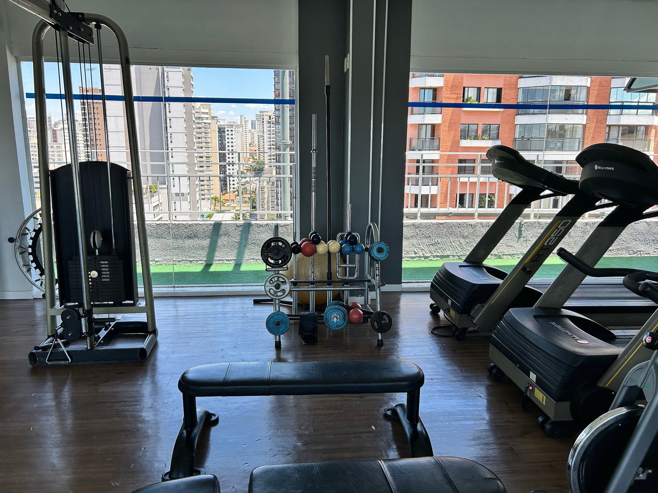Ein Fitnessstudio mit Laufband, Langhantelbank und Kraftgeräten.