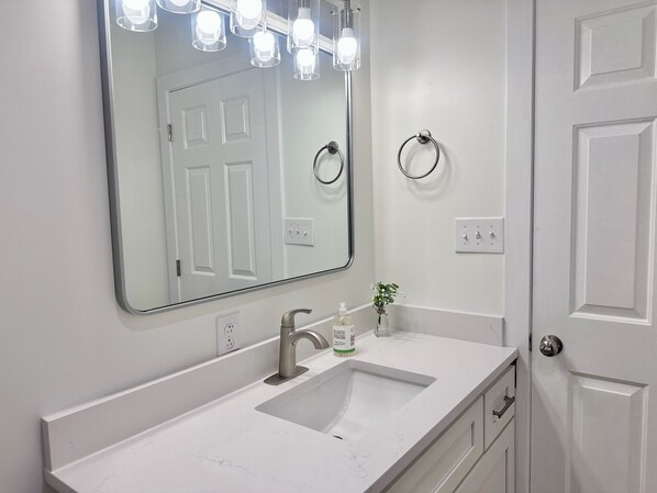 A bathroom with a white sink, a large mirror, and a towel ring.
