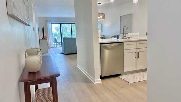 Una cocina moderna con electrodomésticos de acero inoxidable, un comedor con un jarrón y una mesa, y vistas a un balcón.