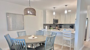 Una cocina moderna con armarios blancos, una isla central e iluminación colgante.