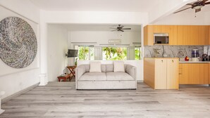 A spacious living area with a grey sofa, wooden cabinets, and a ceiling fan.