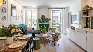 Een moderne woonkamer met een bank, eettafel, stoelen en een groot raam.