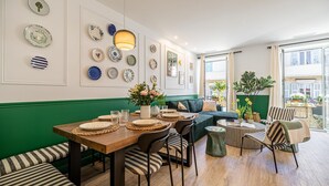 Een eetruimte met een houten tafel gedekt voor vier personen, groene bekleding en diverse decoratieve borden aan de muur.