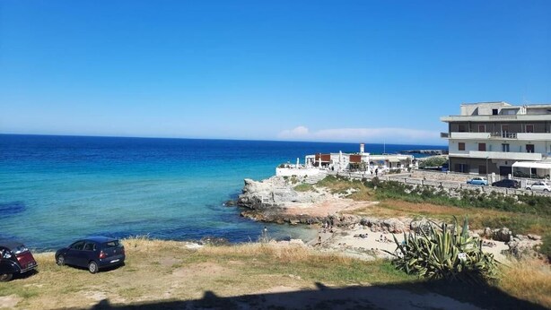 Vista sulla costa con un complesso di edifici, cielo sereno e l'oceano.