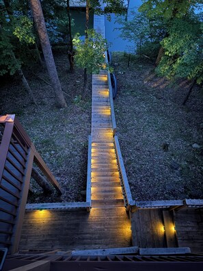 A wooden staircase with railings, surrounded by trees and foliage.
