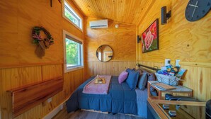 Une chambre confortable dans un chalet, avec un lit, une petite table, un miroir et une horloge murale.