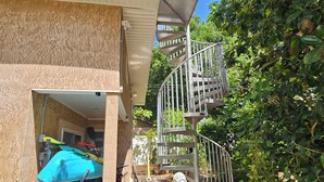 Il s’agit d’une propriété résidentielle dotée d’un escalier en colimaçon, d’un espace extérieur couvert et d’un jardin agrémenté de plantes en pot.