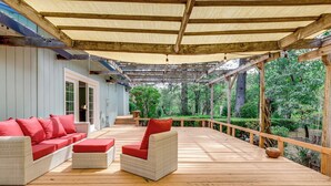 A covered outdoor deck with wicker furniture and a wooden railing. - Pool & Deck: Wine Country Hideaway in Middletown! (Middletown)