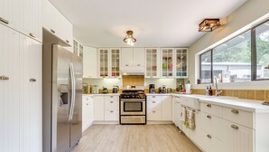 A modern kitchen with white cabinetry, stainless steel appliances, and a large window providing natural light. - Pool & Deck: Wine Country Hideaway in Middletown! (Middletown)
