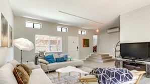 A spacious living room with a sofa, a television, and a staircase leading to another level. - Pool & Deck: Wine Country Hideaway in Middletown! (Middletown)