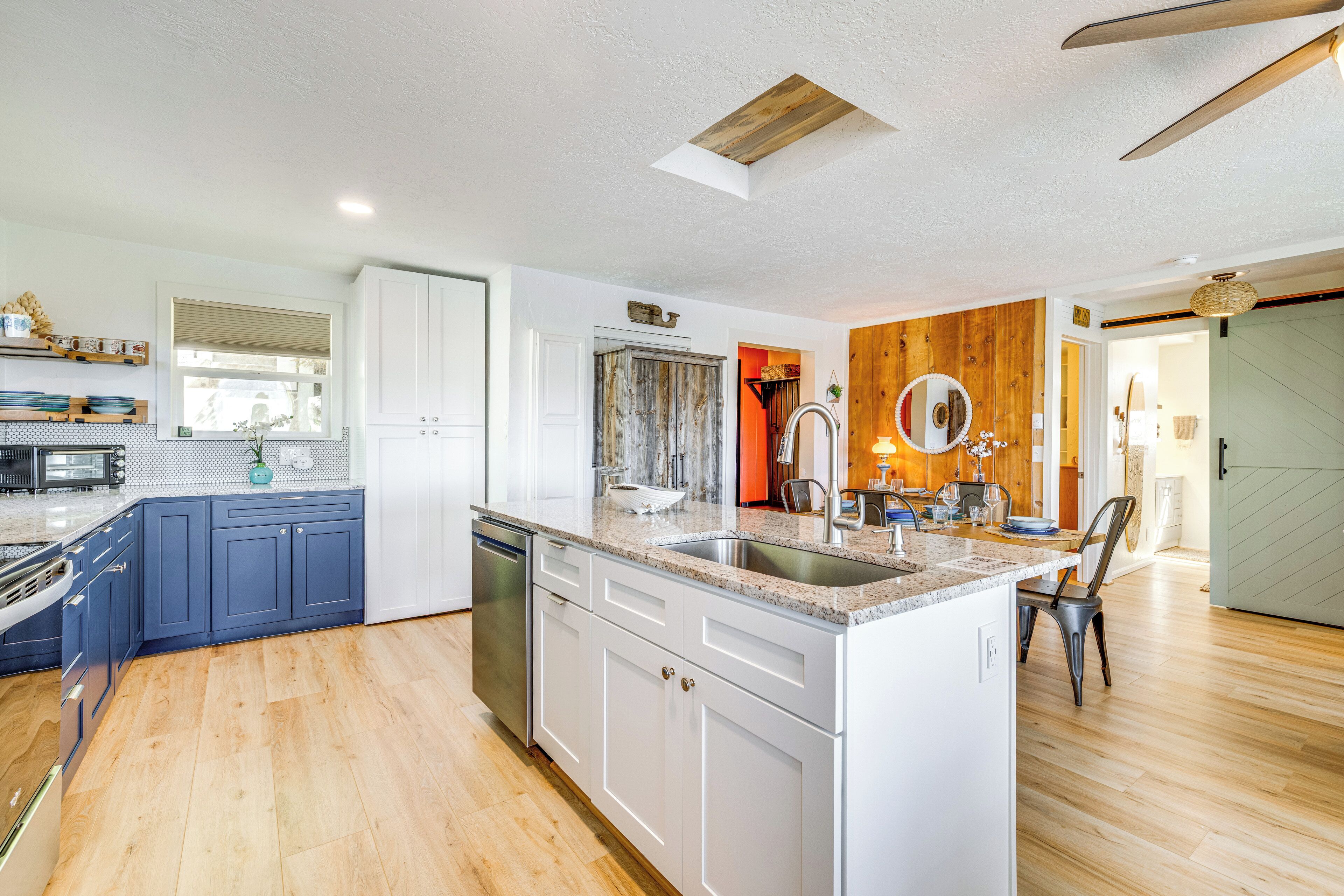 A modern kitchen with white and blue cabinets, a central island, and a wooden accent wall.