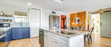 A modern kitchen with white and blue cabinets, a central island, and a wooden accent wall.