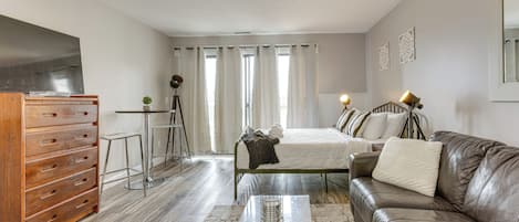 A modern bedroom with a bed, a leather sofa, a desk with a chair, and a TV.