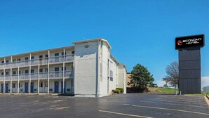 A two-story motel with a central entrance and a parking lot in front. - Economy Hotel Kansas City (Blue Springs)