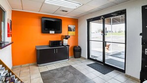 A reception area with a black counter, a television mounted on the wall, and a large glass door leading outside. - Economy Hotel Kansas City (Blue Springs)