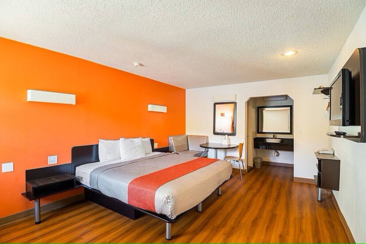 Una habitación de hotel moderna con cama, mesitas de noche, escritorio y televisión.