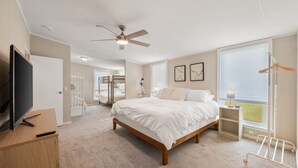 A bedroom with a bed, a ceiling fan, a TV, a desk, and a window with blinds. - Lakefront Family Retreat– Private Dock & Fire Pit​ (Kemp)