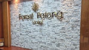 Un espace d’accueil avec un mur en pierre et une enseigne indiquant « Forest Patong Hotel ».