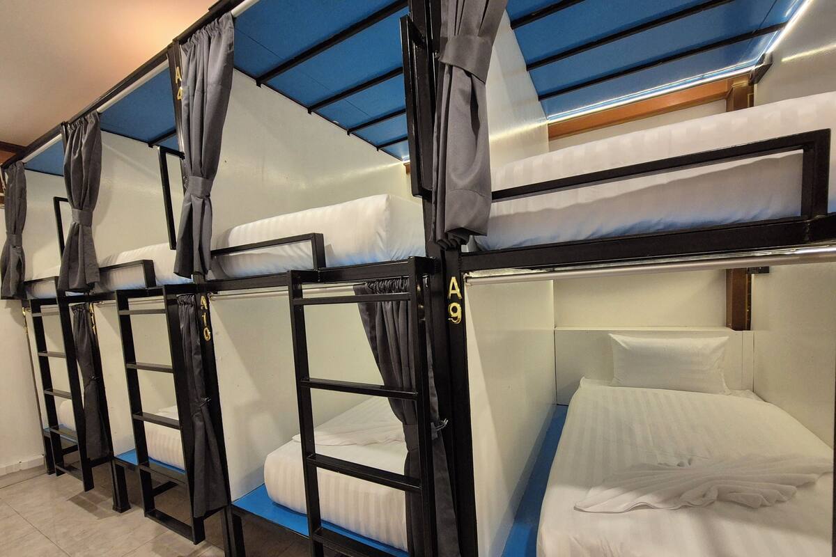 Bunk beds with curtains, a tiled floor, and a blue ceiling.