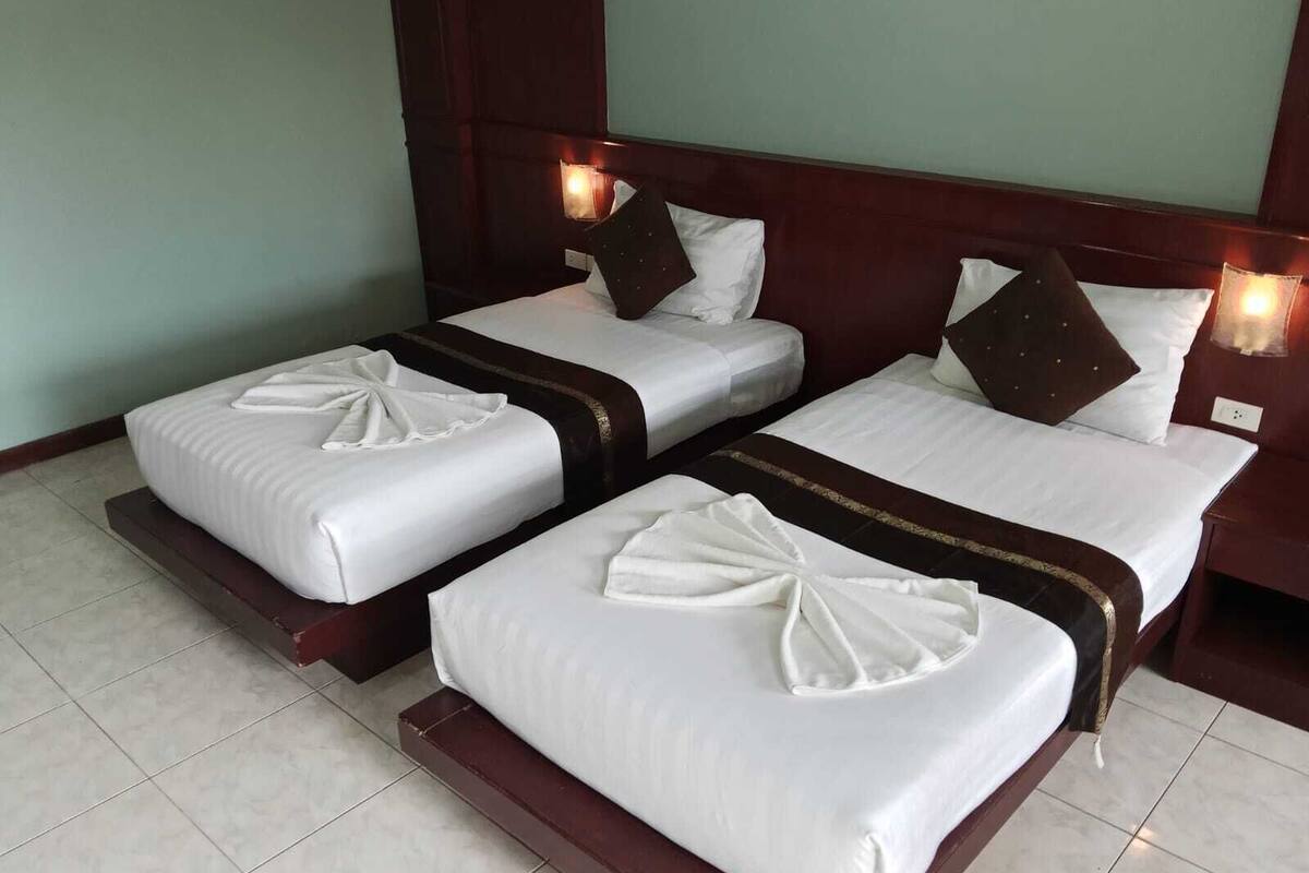 A hotel room with two beds, each with white linens and decorative bows.