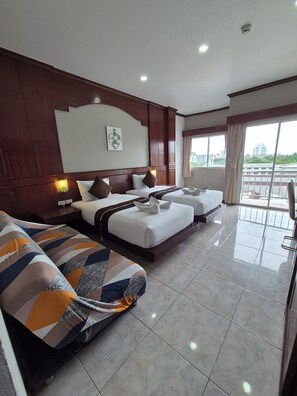 A hotel room with two beds, a sofa, a large window, and a view of the city. - New Forest Patong (Patong)