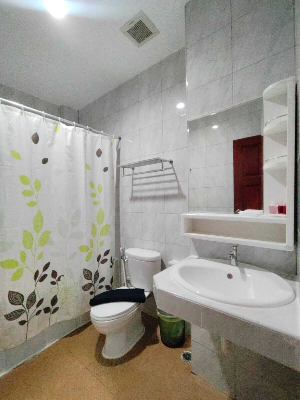 A bathroom with a toilet, sink, and shower curtain.
