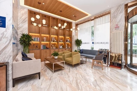 Um hall de hotel moderno com piso de mármore, prateleiras de madeira com objetos decorativos, um sofá, uma mesa de centro e um espaço de estar com vista para a rua.. Super 8 Hotel (Beijing Qianmen Tiantan Park)