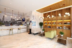A hotel reception area with a marble counter, seating, and a cityscape mural. - Super 8 Hotel (Beijing Qianmen Tiantan Park) (Beijing)