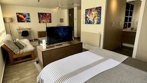 A modern bedroom with a large bed, a TV, a desk, and artwork on the walls.