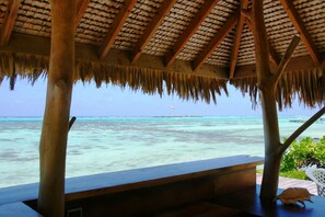 A beachside structure with a thatched roof overlooking turquoise waters.