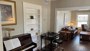A living room with a piano, a glass table, a sofa, and a chair.