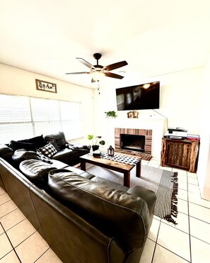 Relax by the fireplace in this cozy living room with a sofa, coffee table, and flat-screen TV.