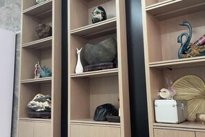 A wooden shelving unit with decorative items and a white object on the bottom shelf. - Serinity Hotel (Yangshuo West Street Lijiang Branch) (Yangshuo)