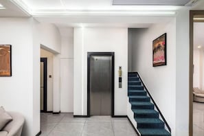 A hotel lobby with a staircase, elevator, and a sofa.