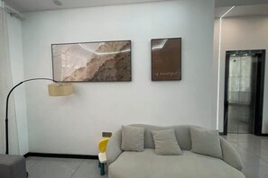 Um interior moderno com um sofá, um abajur e duas obras de arte penduradas na parede.