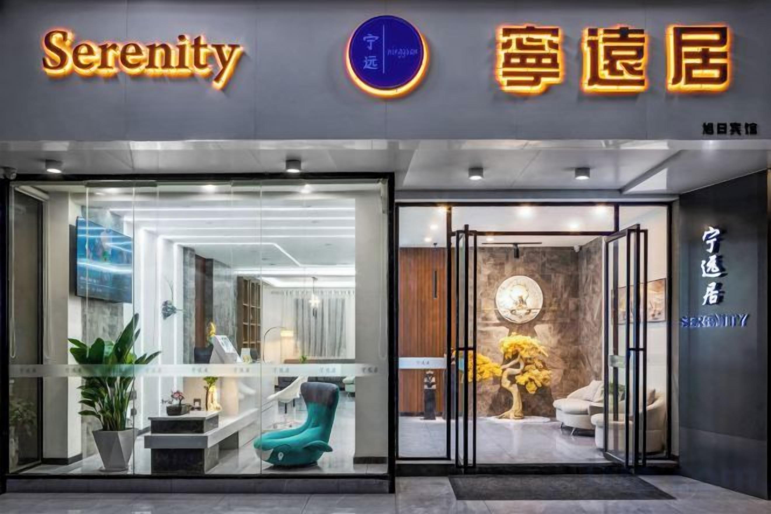 A hotel entrance with a glass facade, a reception desk, and a visible interior with seating and decor.