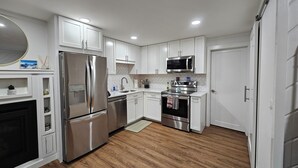Une cuisine moderne avec des armoires blanches, des appareils en acier inoxydable et un dosseret de carrelage disposé en motif chevron.