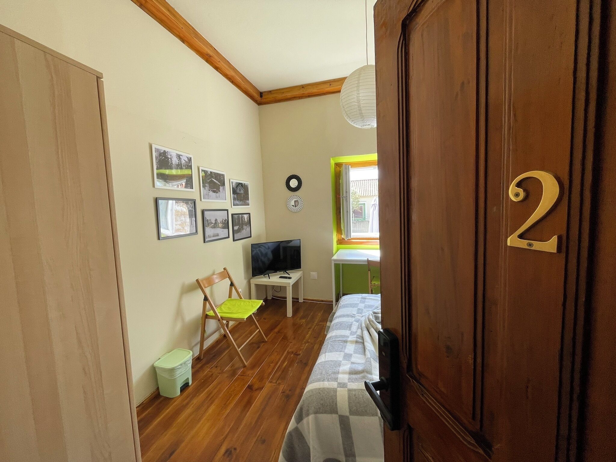 Une chambre à coucher avec un lit, un bureau, une chaise, une télévision et une fenêtre.