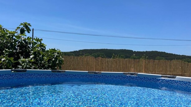 Een zwembad met helderblauw water, omgeven door een houten hek en bomen.