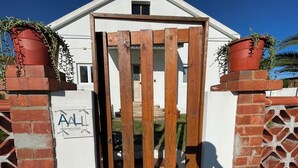 Een omheind toegangspunt met een houten poort, bakstenen pilaren en potplanten.