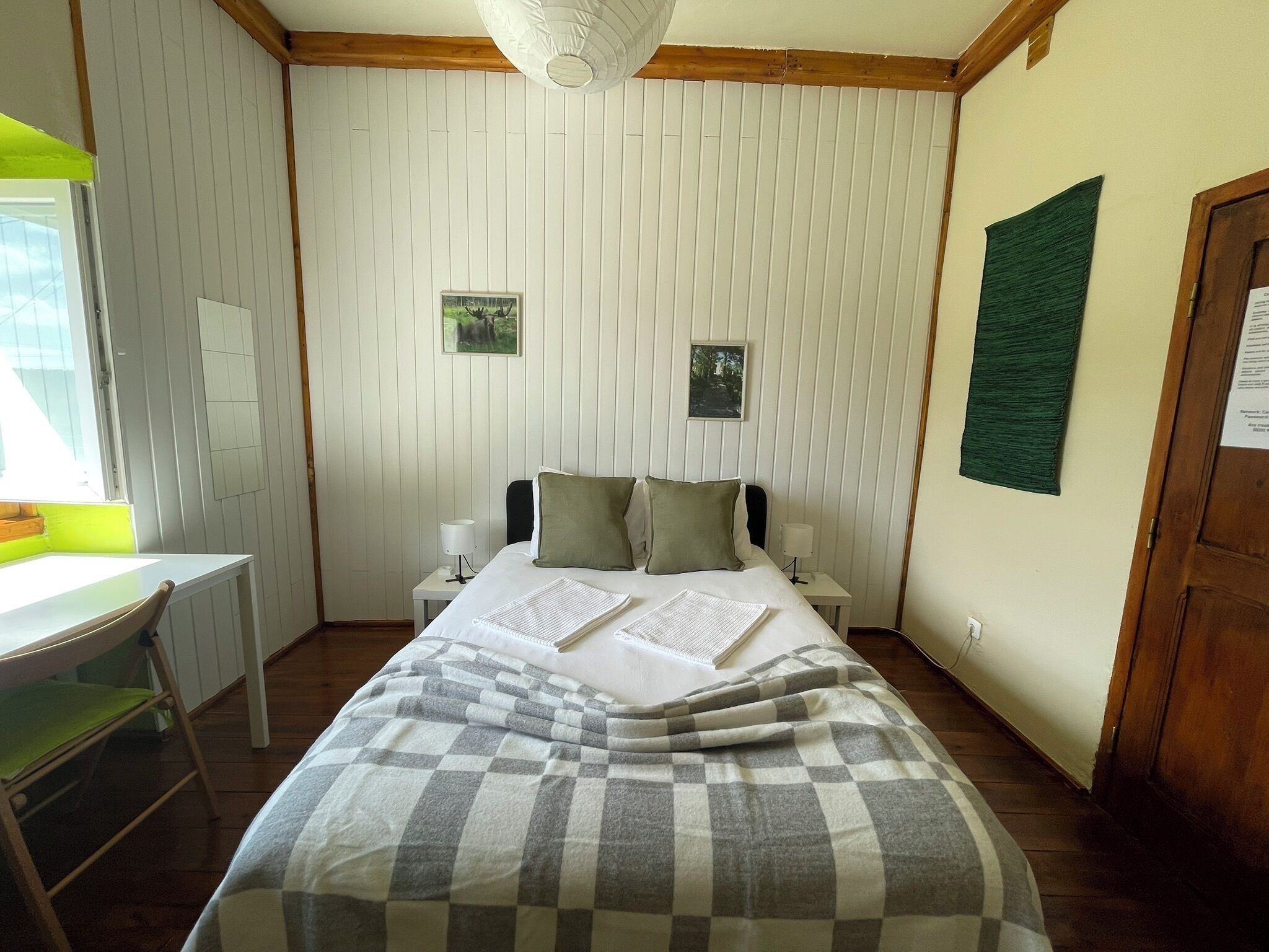 A bedroom with a bed, bedside tables, a desk, and a chair.