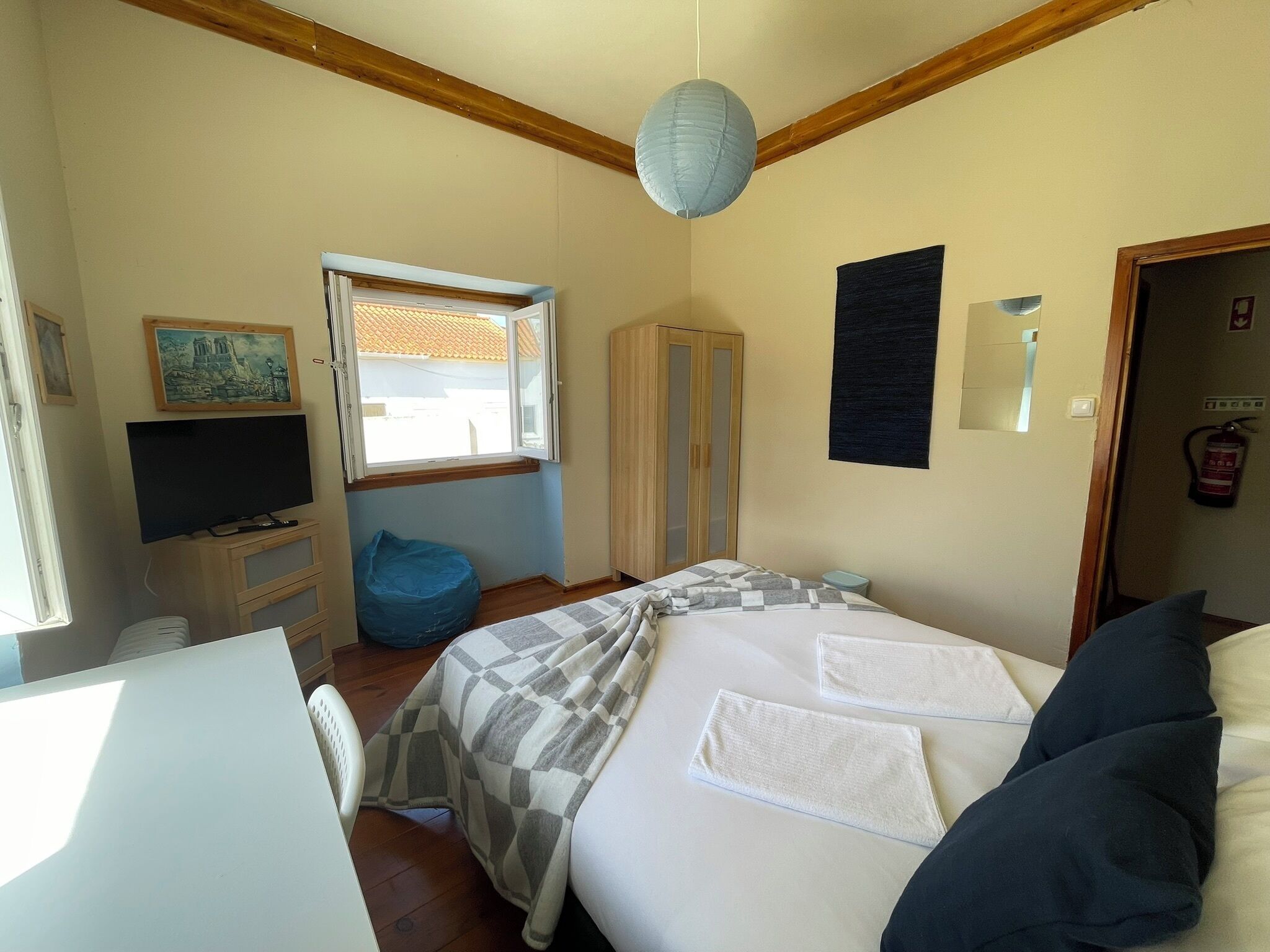 Un dormitorio con una cama, televisión, armario, ventana y puerta.