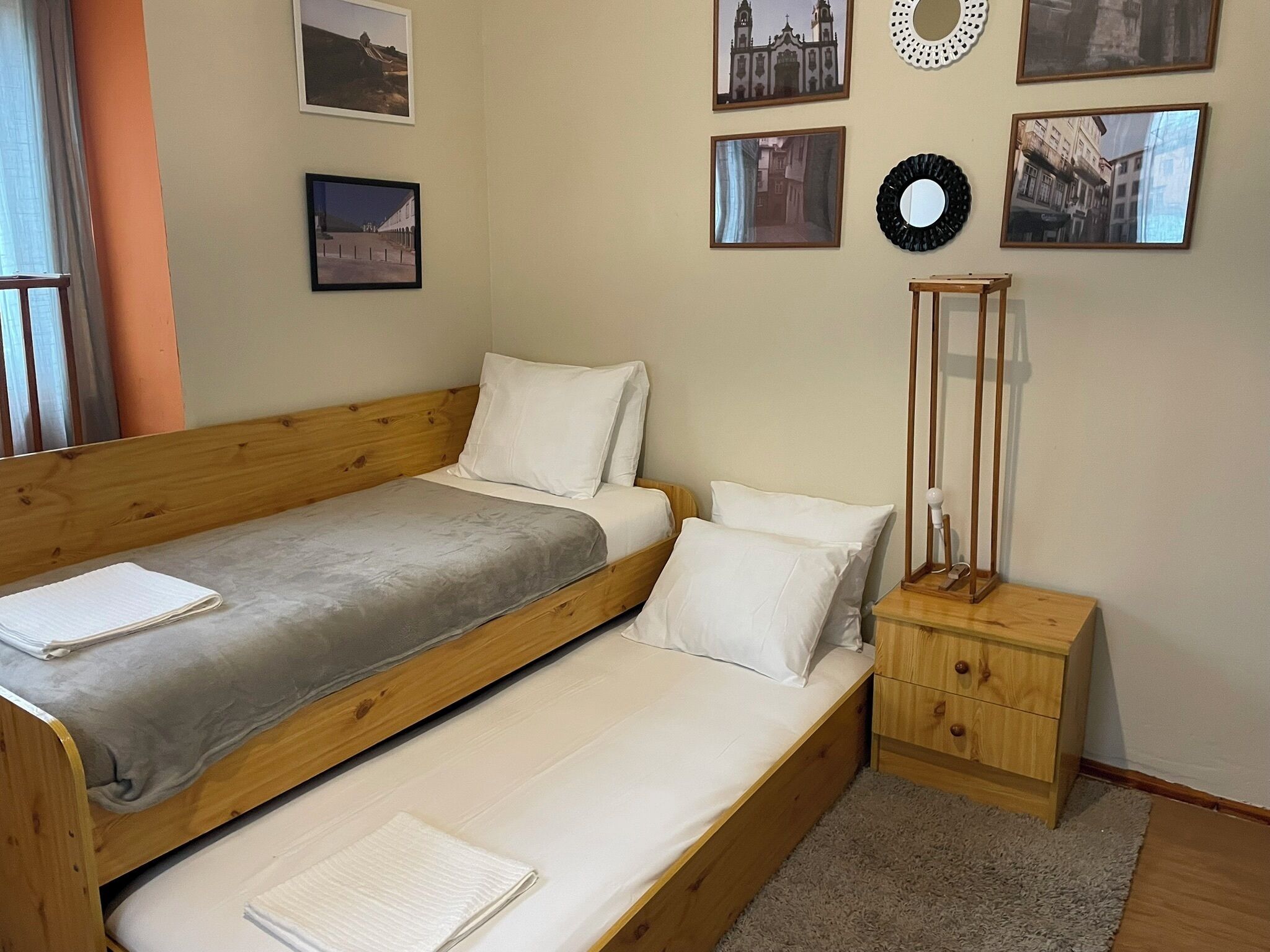 Habitación individual con una cama de una sola plaza, cabecera de madera, mesita de noche con cajones y un espejo.