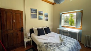 Een slaapkamer met een bed, een bureau, een raam met uitzicht en een deur.