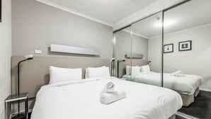 Ein Hotelzimmer mit zwei Betten, einem großen Spiegel und einem kleinen Tisch.