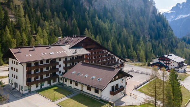 A multi-story building with a flat roof, surrounded by a mountainous landscape. - Principe Marmolada 817/A (Rocca Pietore)