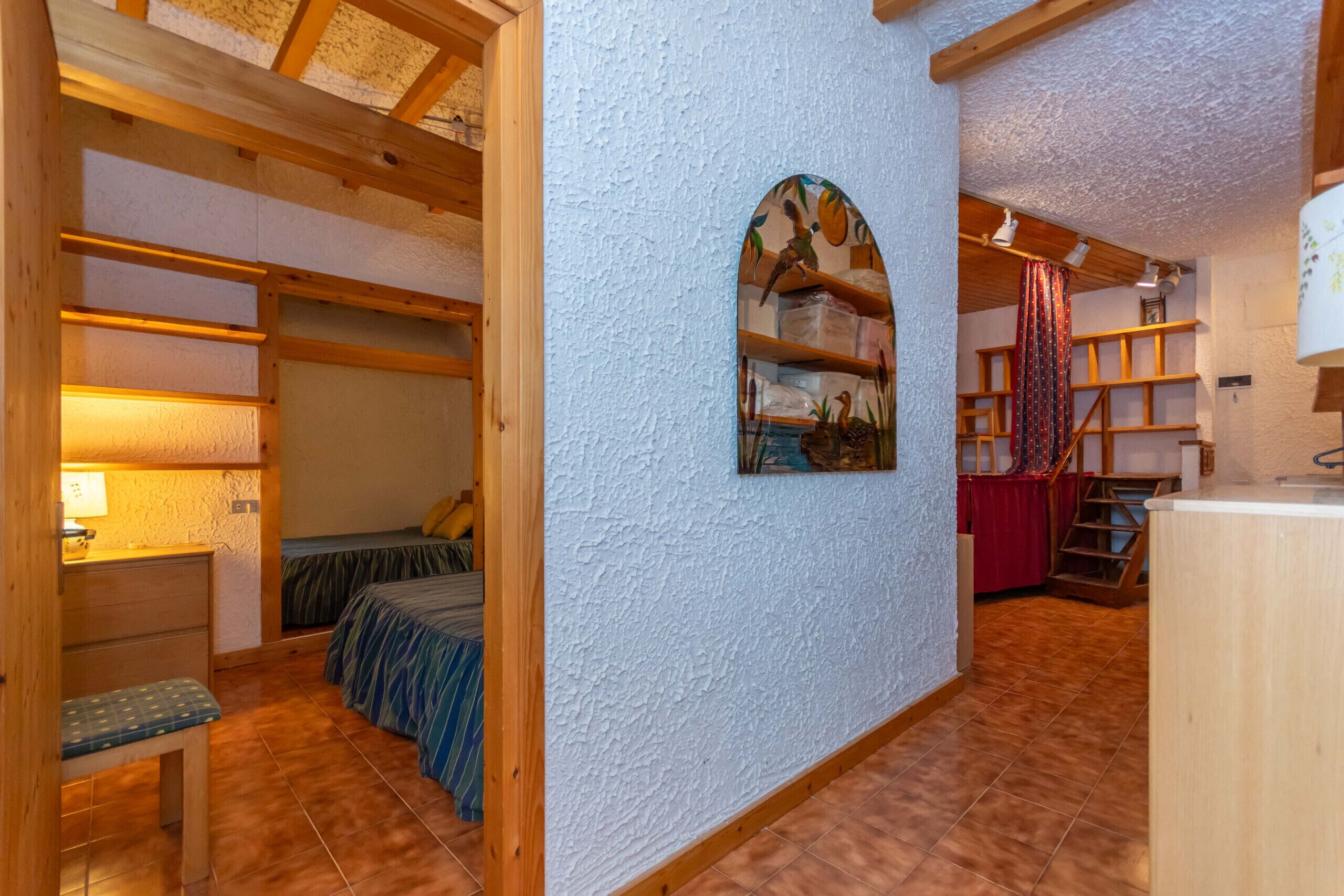 Ein gemütliches Zimmer mit einem Bett, einem Schreibtisch und einem Regal mit Dekoration.